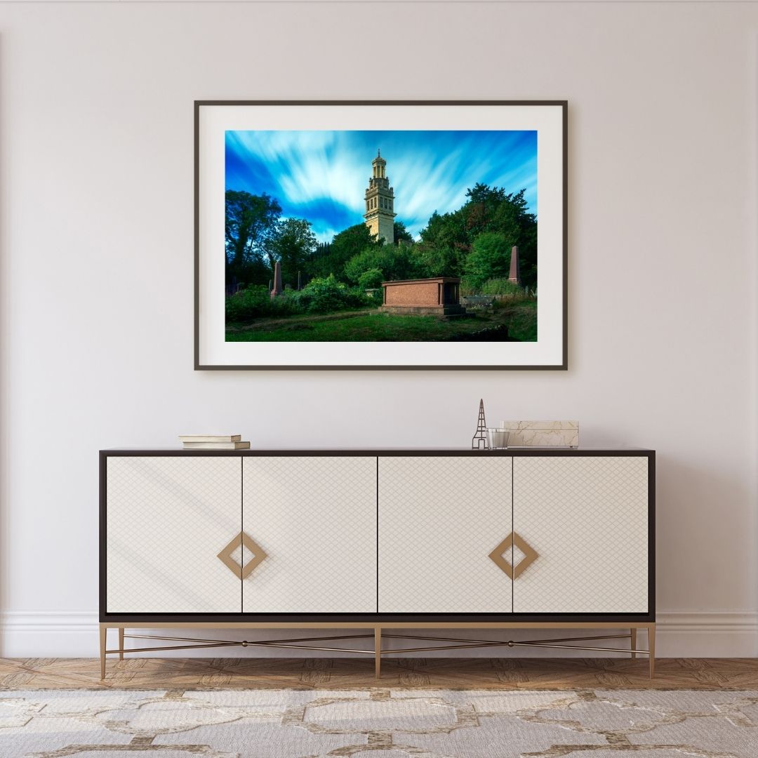 Framed photograph of a scenic landscape above a decorative cabinet.