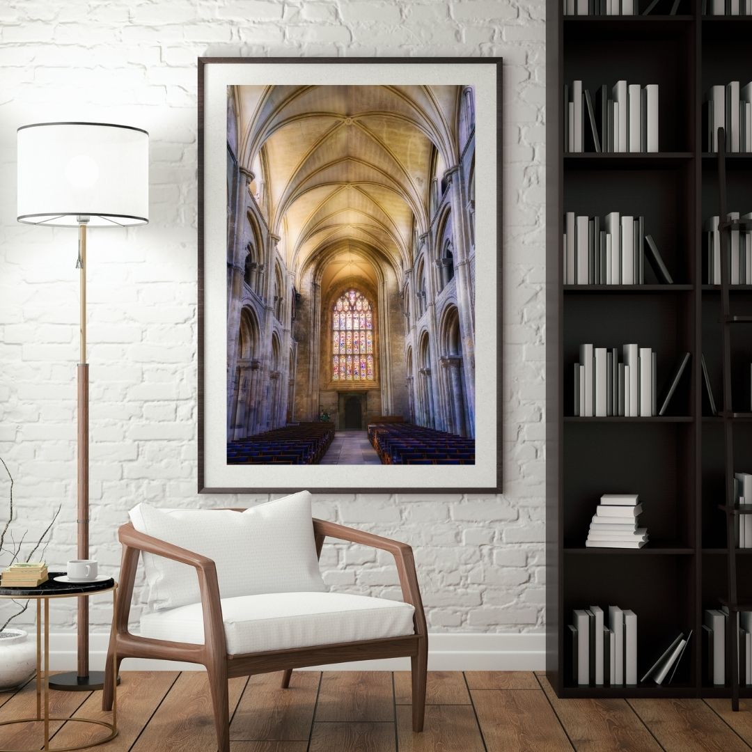 Framed artwork of a cathedral interior in a living room setting with a chair and bookshelf.