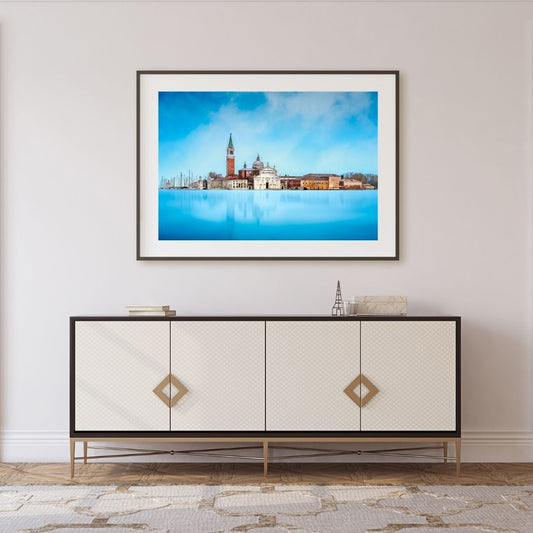 Framed artwork of Venice above a decorative cabinet in a room.