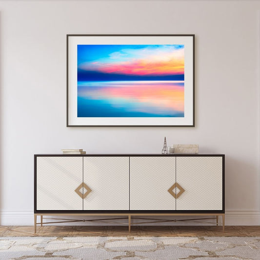Framed abstract artwork above a decorative cabinet in a room.