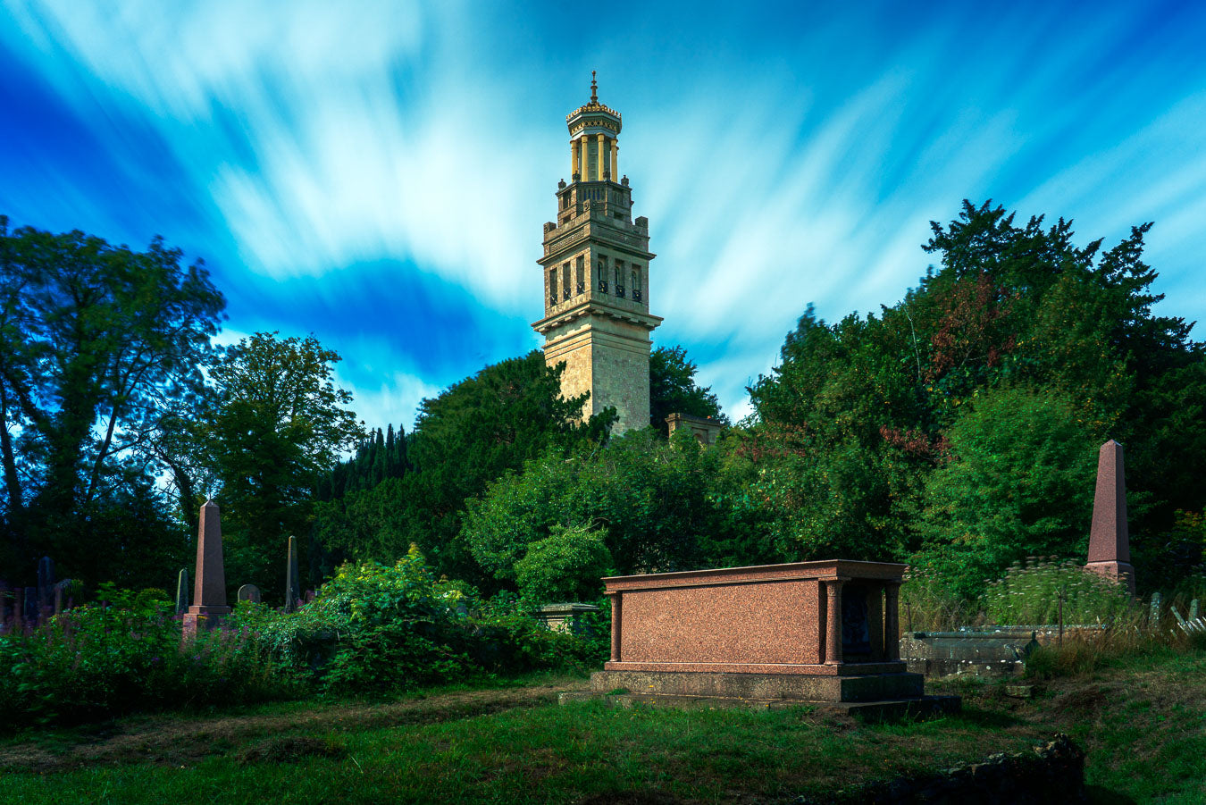 Long-exposure photograph of Beckford’s Tower in Bath, surrounded by trees and gravestones under a motion-blurred sky