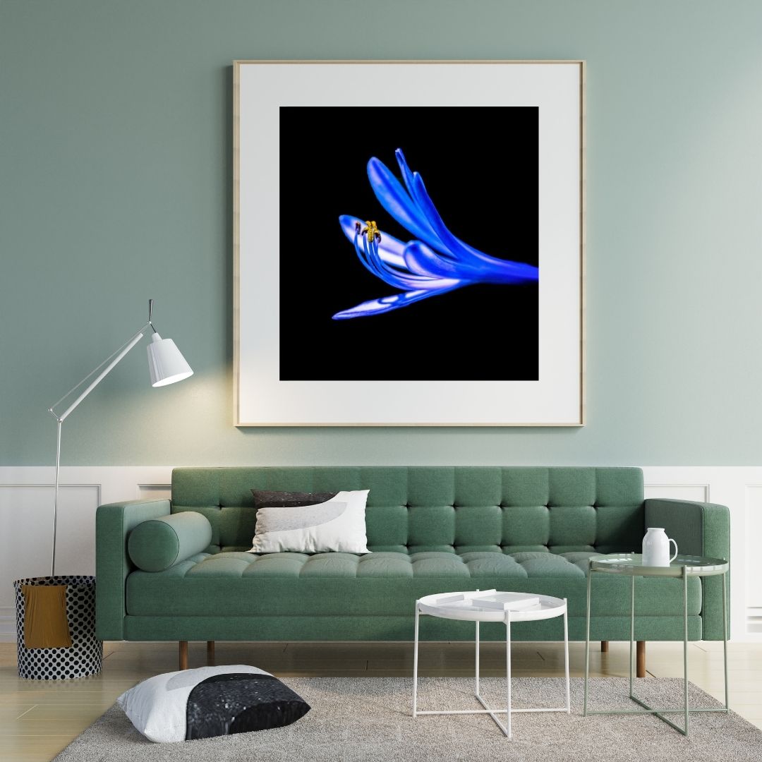 Modern living room with a green sofa, abstract art on the wall, and a lamp.