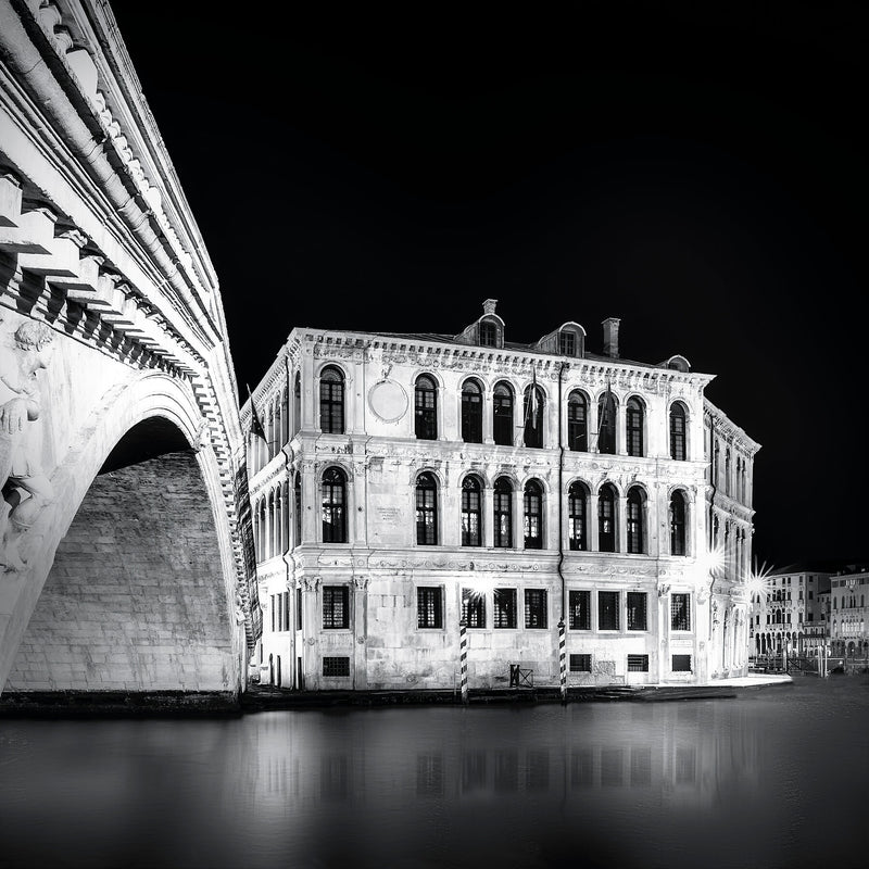 Beneath the Rialto, at night, in Venice, Italy, with calm water