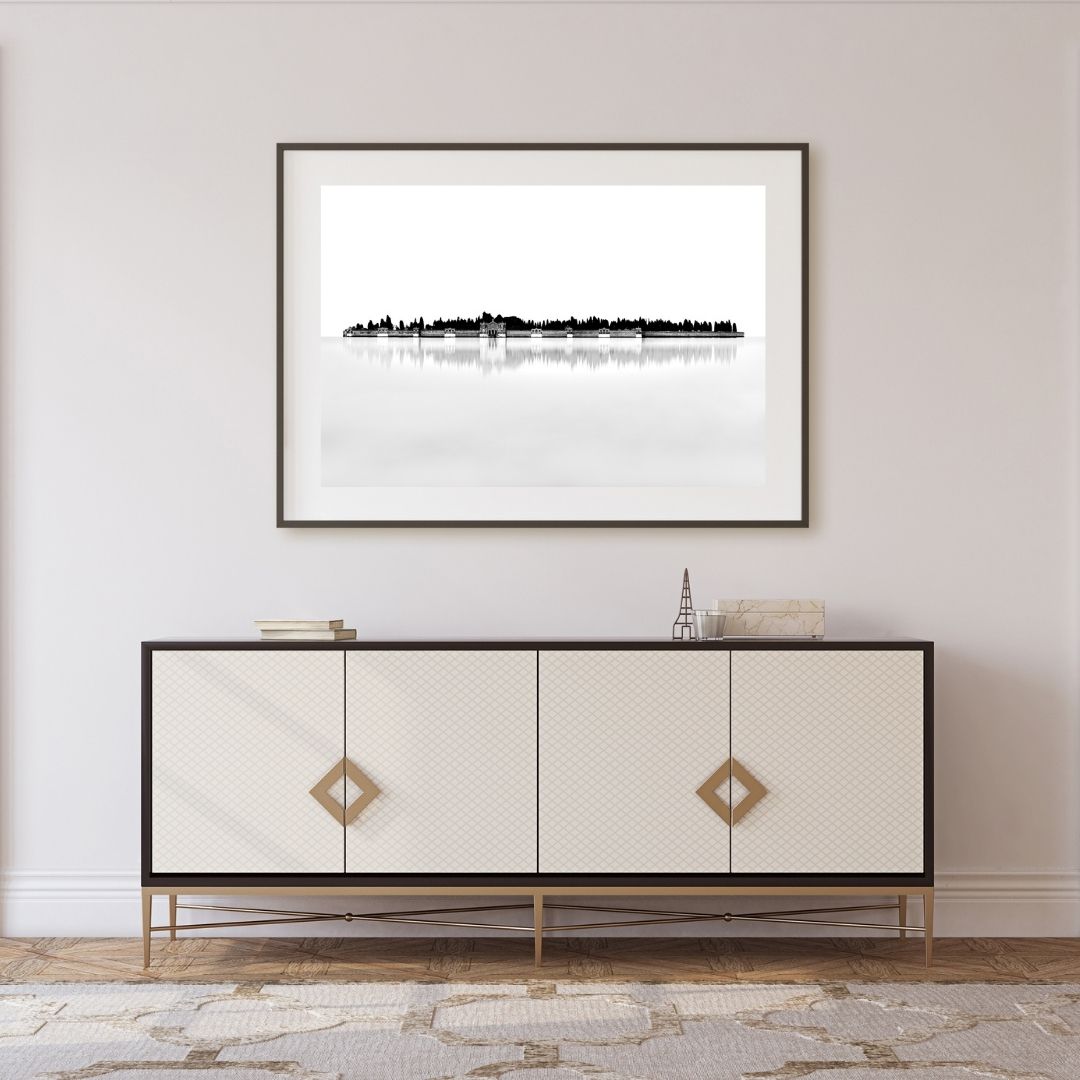 Framed black and white artwork above a decorative cabinet in a room.