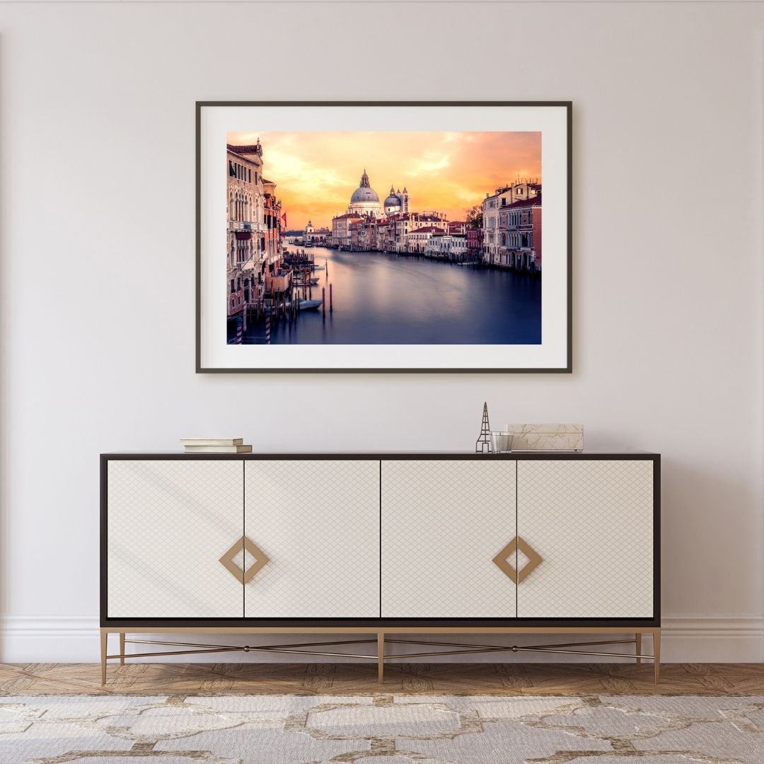 Framed artwork of Venice cityscape above a decorative cabinet in a room.