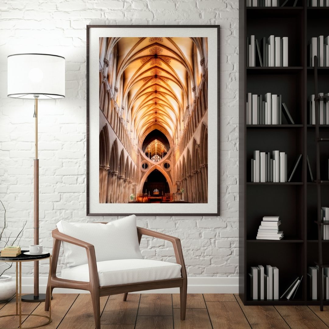 Framed artwork of Wells cathedral interior in a living room setting with a chair and lamp.
