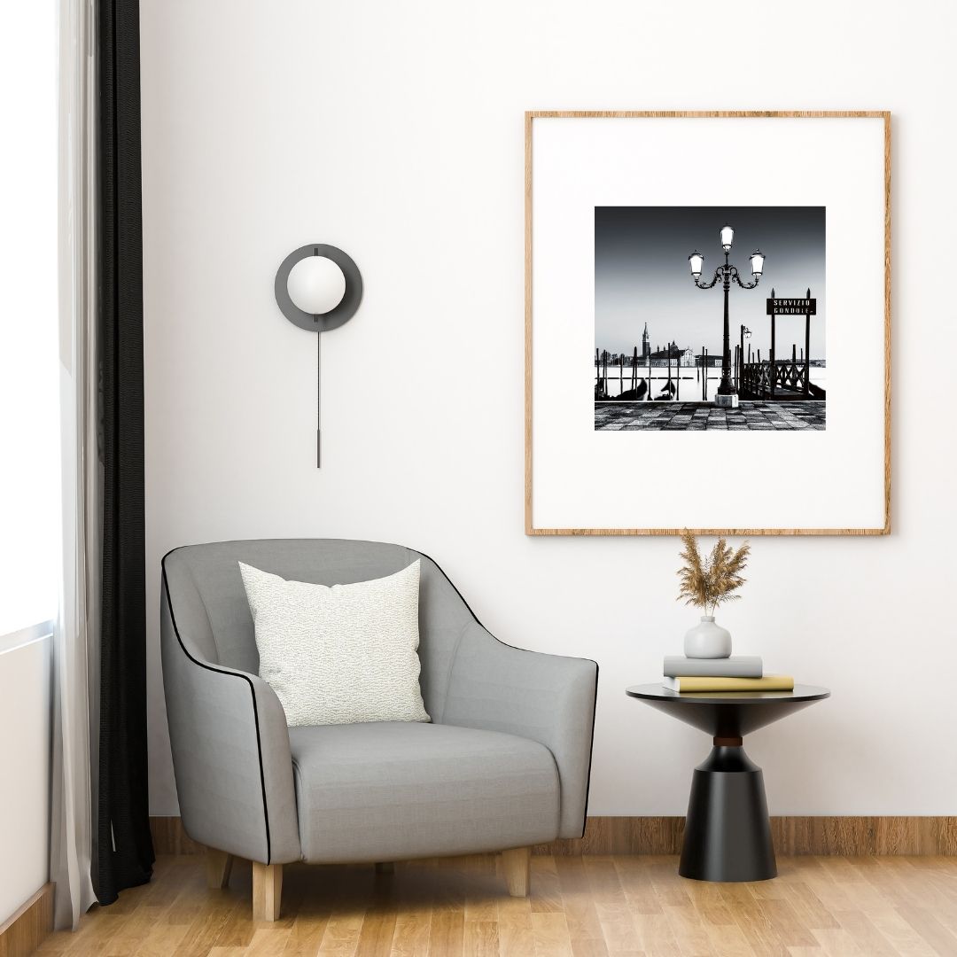 Modern living room with a gray armchair, side table, and framed artwork on the wall.