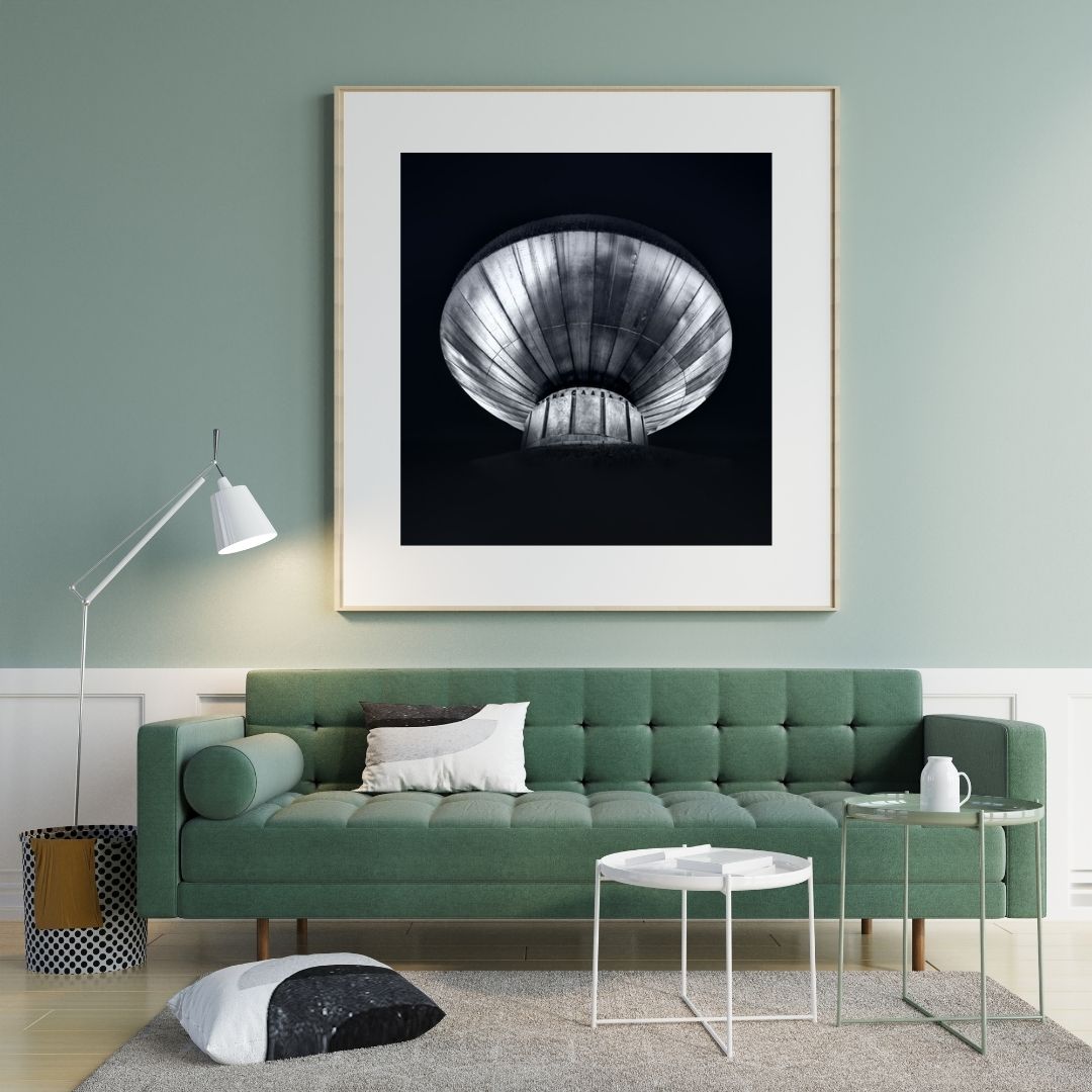 Modern living room with a green sofa, framed artwork on the wall, and a lamp.