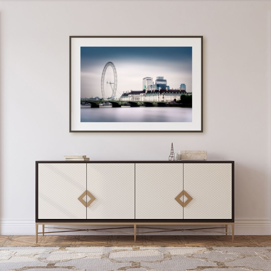 Framed artwork of a London cityscape with a Ferris wheel above a white sideboard.