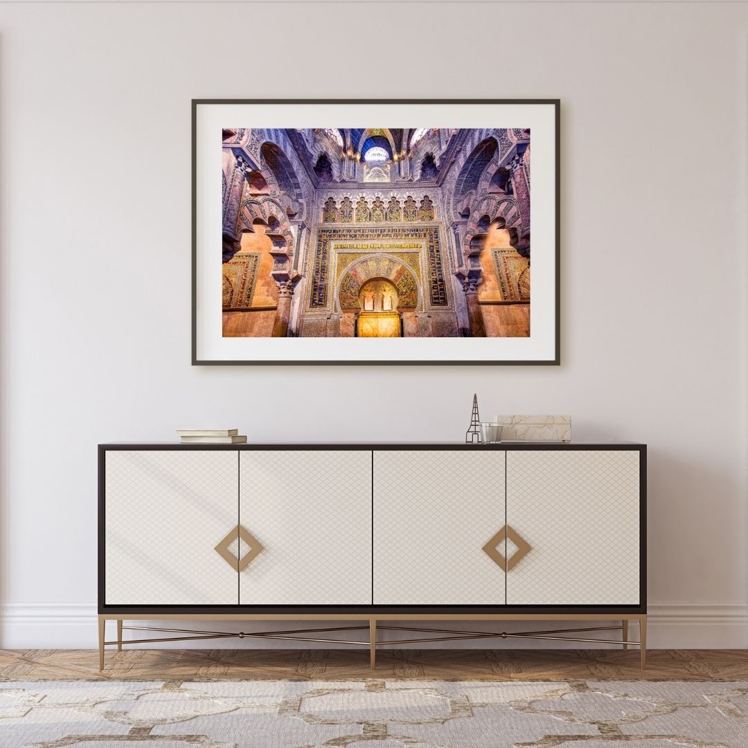 Framed artwork of a architectural interior above a decorative cabinet.