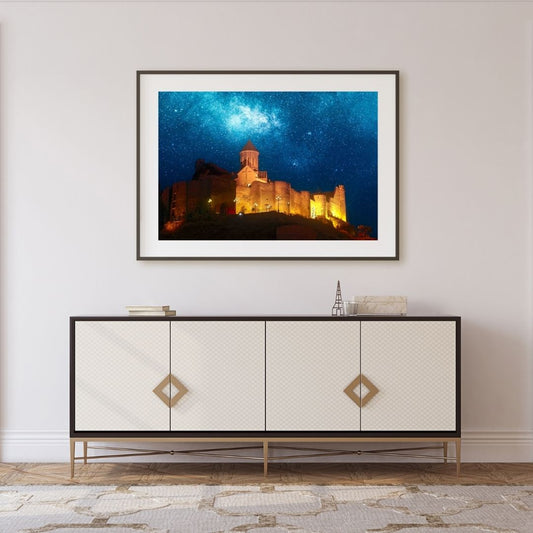 Framed artwork of a castle under a starry sky above a decorative cabinet.