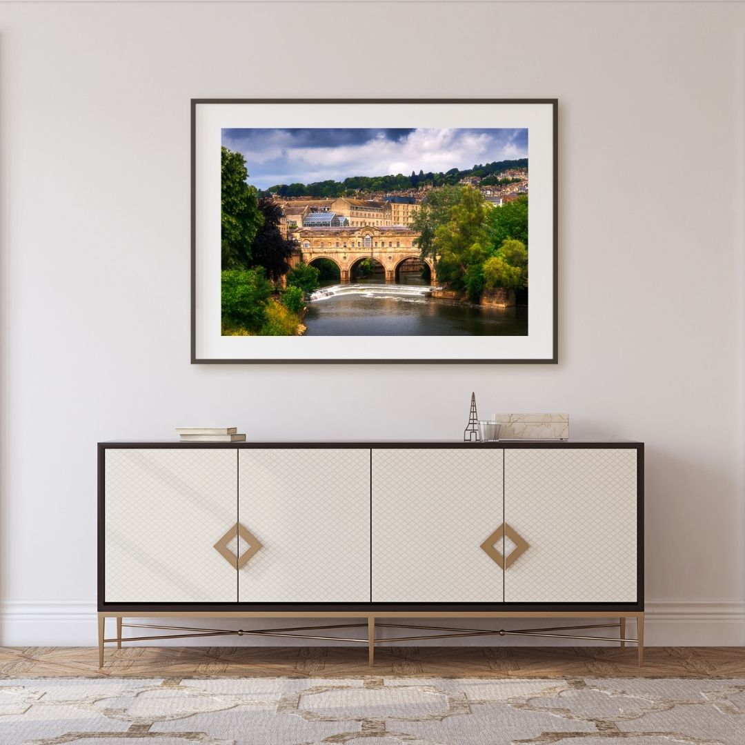 Framed artwork of a scenic landscape above a decorative cabinet.