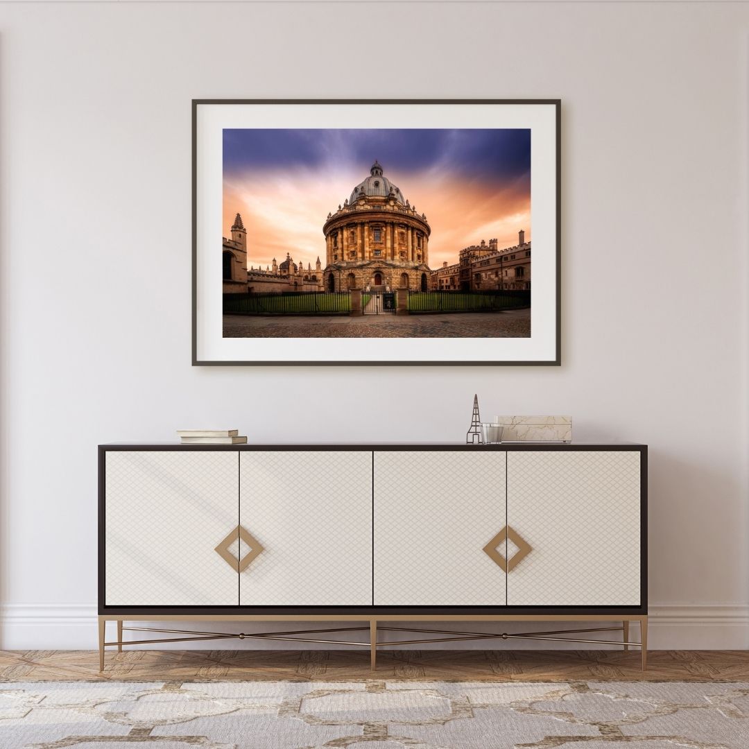 Framed photograph of a architectural building on a wall above a decorative cabinet.