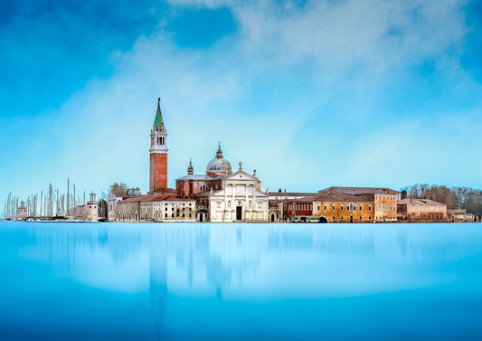 Fine art photograph of San Giorgio Maggiore in Venice reflected in the calm blue waters of the lagoon, with a softly darkened sky and historic architecture.