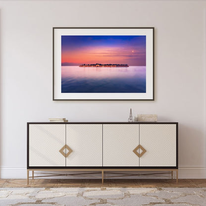 Framed artwork of San Michele at sunset over water above a decorative cabinet.