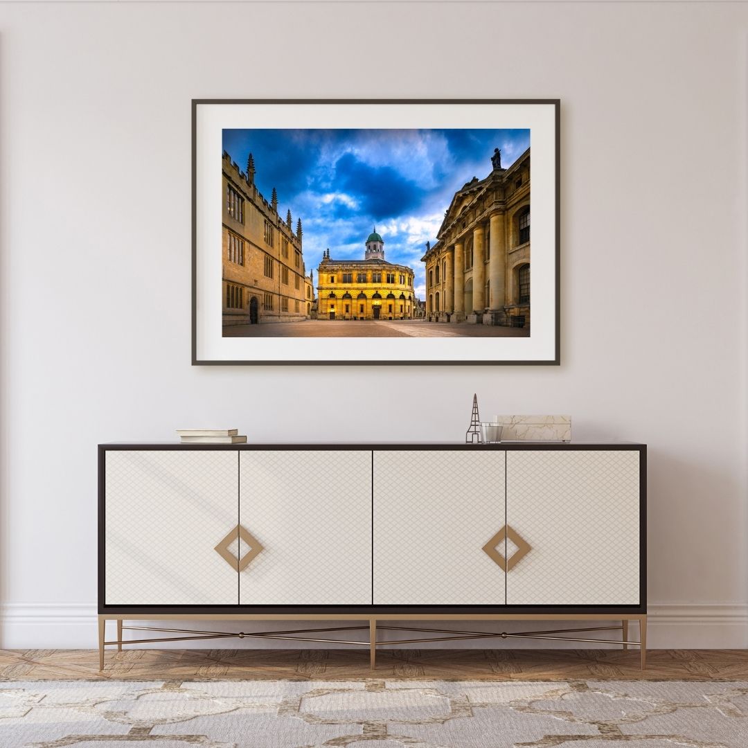 Framed photograph of Oxford above a decorative cabinet.