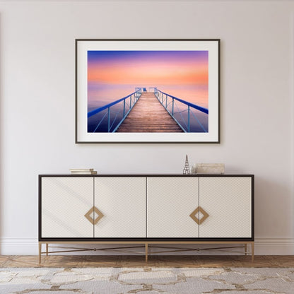 Framed artwork of a sunset over a dock above a decorative cabinet.