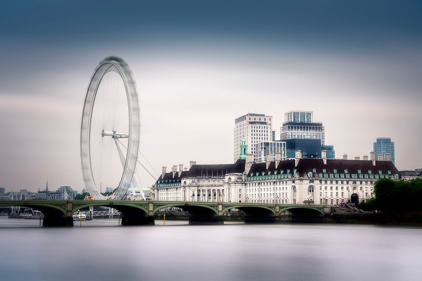 Fine art photograph of the London Eye and County Hall across the River Thames on a calm winter morning, with smooth water and a misty sky.
