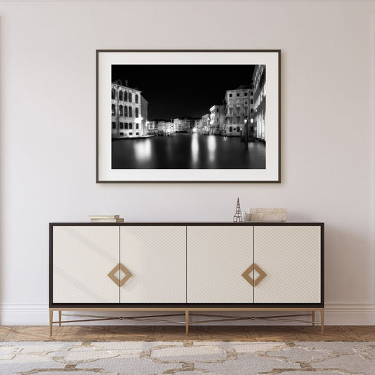 Framed black and white artwork above a decorative cabinet in a room.