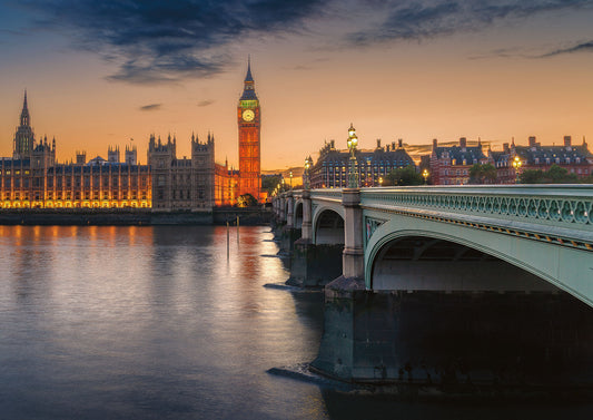 Twilight photograph of the Houses of Parliament and Big Ben seen from Westminster Bridge, with warm evening light and reflections on the River Thames.