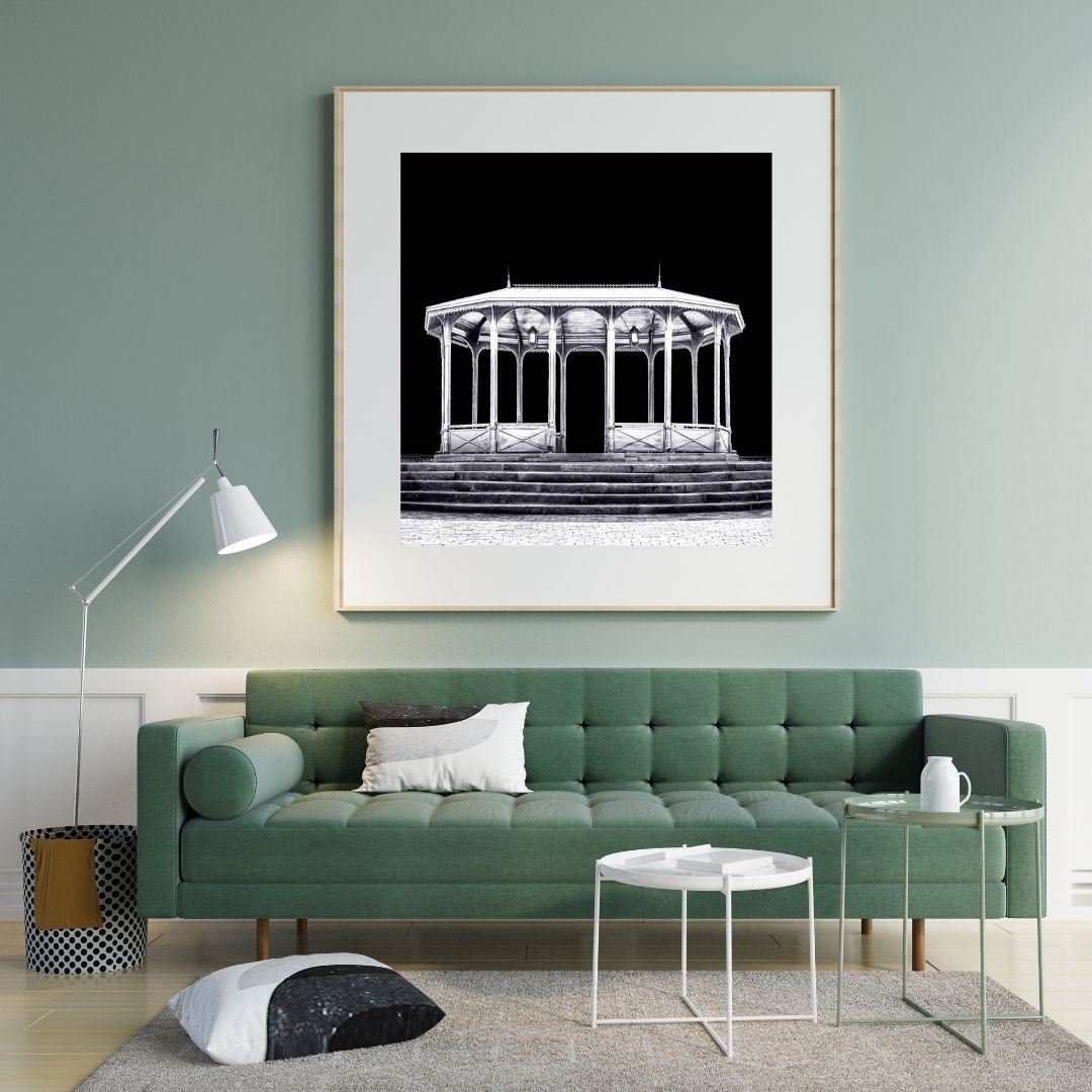 Living room with a green sofa, framed artwork on the wall, and a lamp.