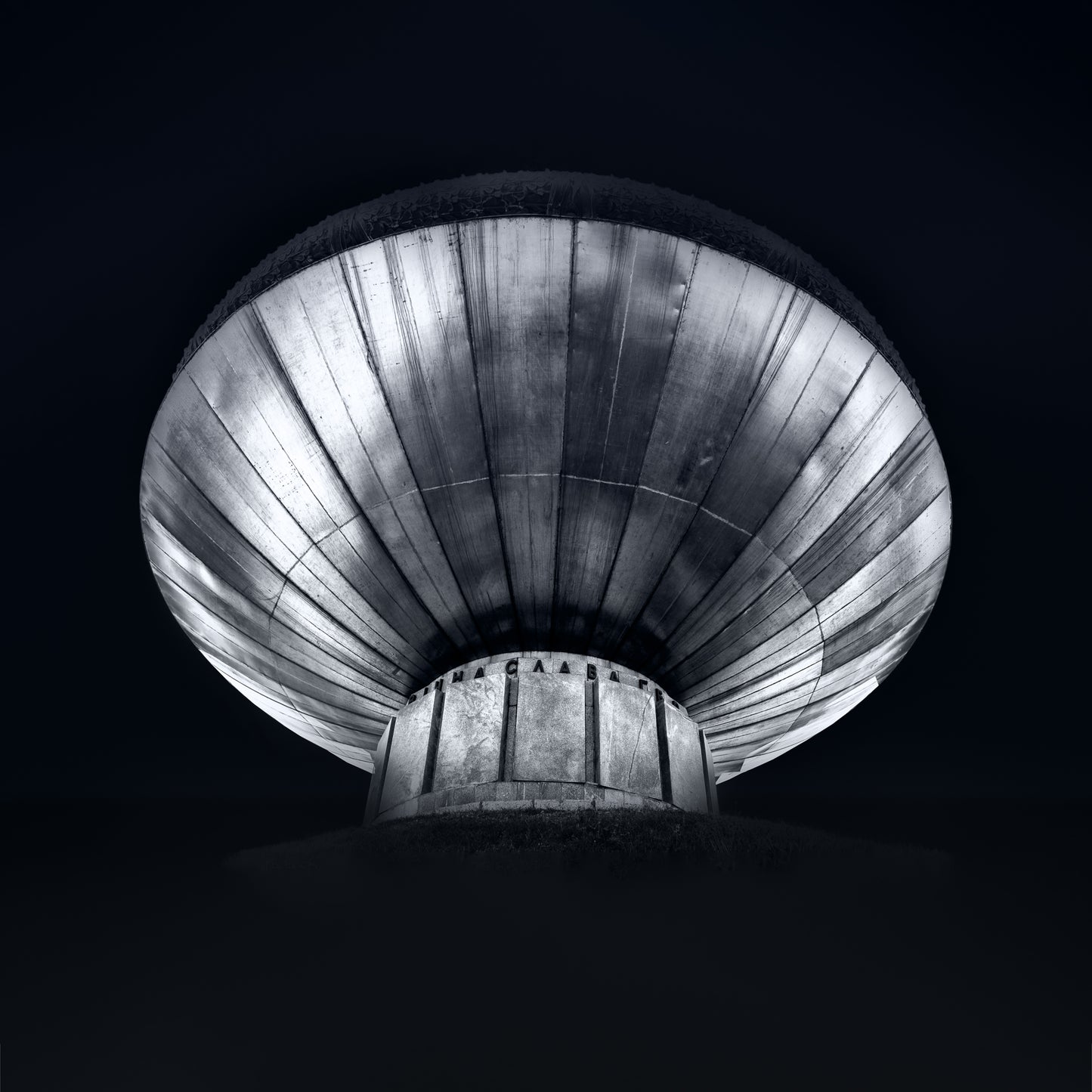 Black and white photograph of a Kyiv monument viewed from below emphasising circular form and dramatic structure