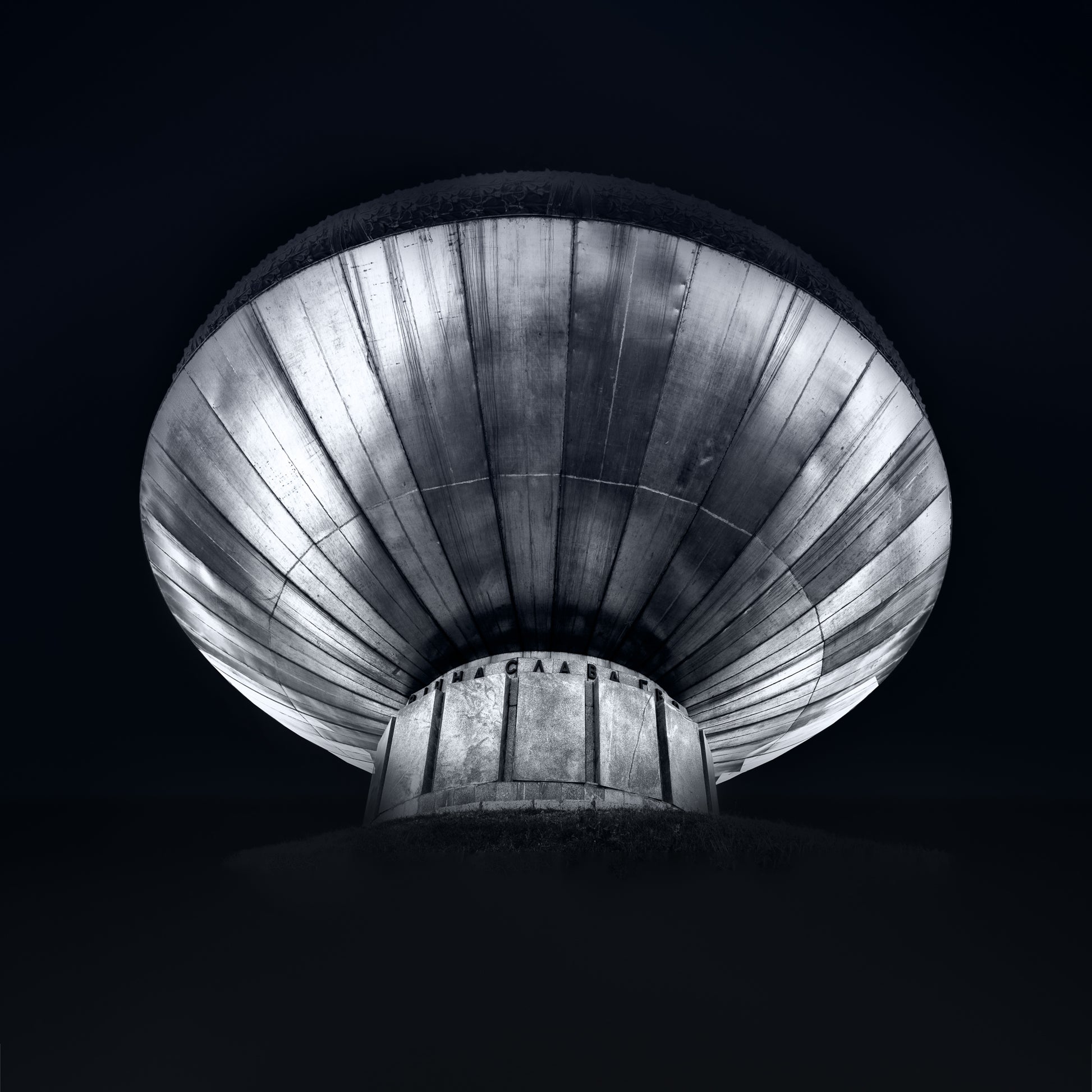 Black and white photograph of a Kyiv monument viewed from below emphasising circular form and dramatic structure