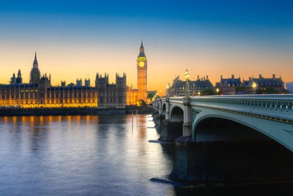 Big Ben and the Houses of Parliament at sunset with Westminster Bridge and soft reflections on the River Thames.