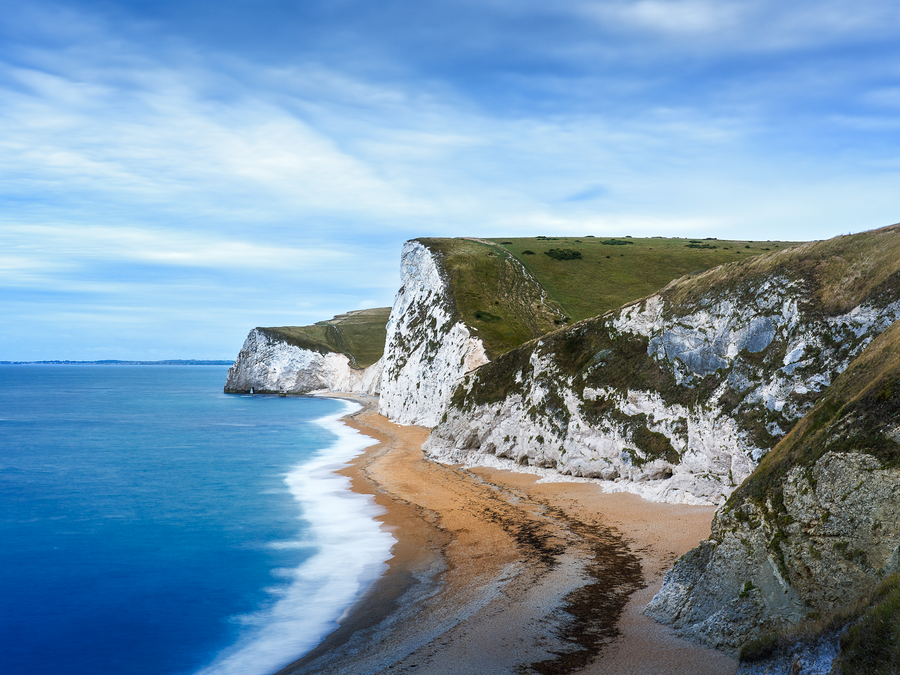 Colour photograph of chalk cliffs near Durdle Door Dorset with a sweeping coastline and smooth long exposure sea.