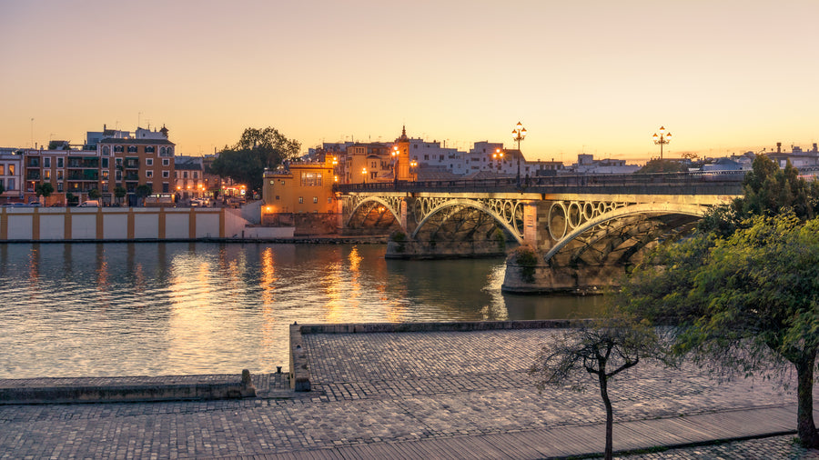 Isabel II Bridge in Seville at sunset with warm evening light reflecting on the Guadalquivir River