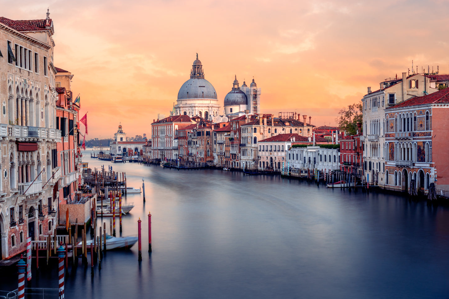 Colour photograph of the Grand Canal in Venice at sunset with Santa Maria della Salute and historic buildings reflected in calm water