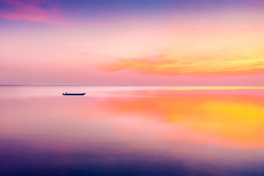 A fine art photograph near Kyiv, Ukraine, showing a small boat on still water at sunrise with soft pastel light and calm reflections.