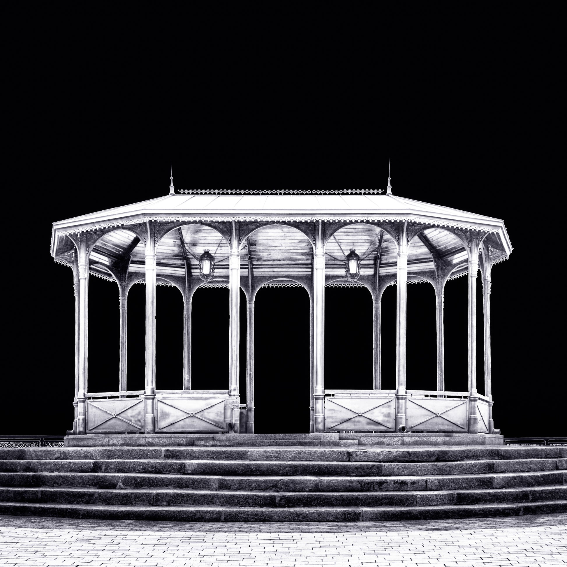 A fine art black and white photograph from Kyiv, Ukraine, showing a viewing pavilion illuminated at night against a dark sky.
