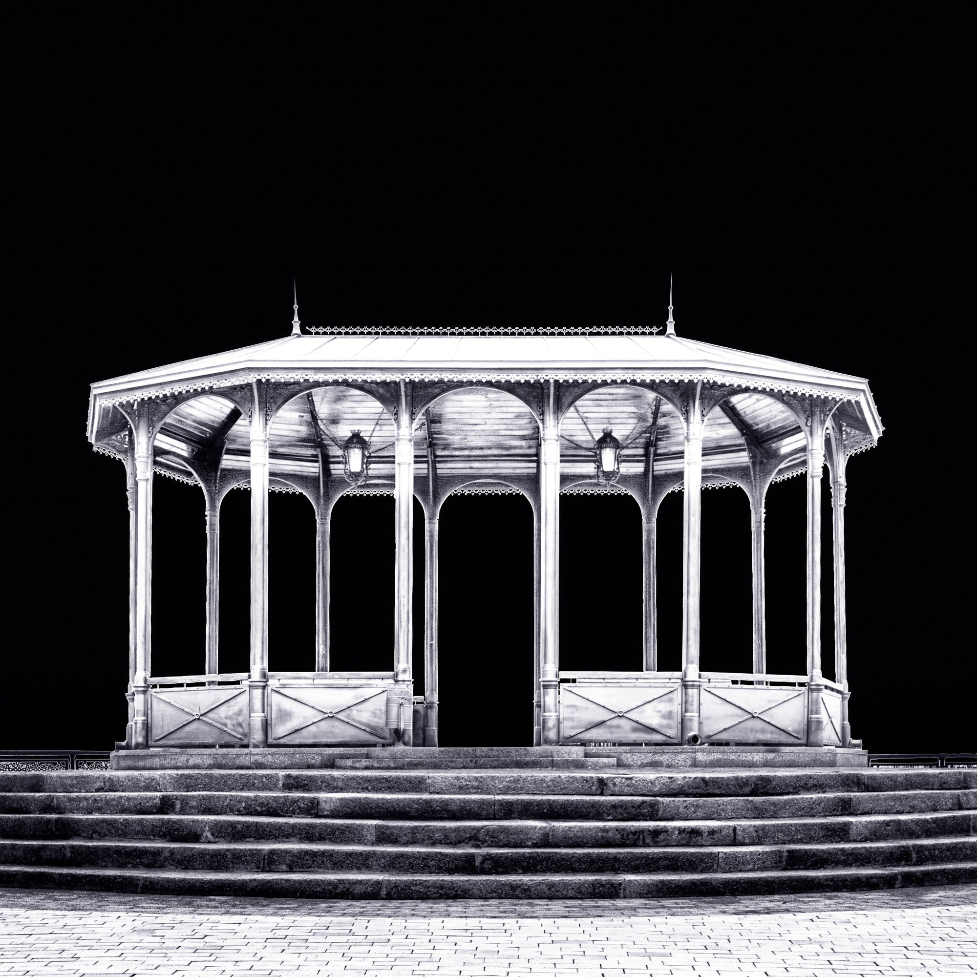 A fine art black and white photograph from Kyiv, Ukraine, showing a viewing pavilion illuminated at night against a dark sky.