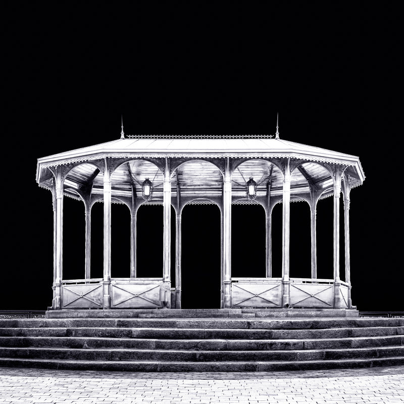 A fine art black and white photograph from Kyiv, Ukraine, showing a viewing pavilion illuminated at night against a dark sky.