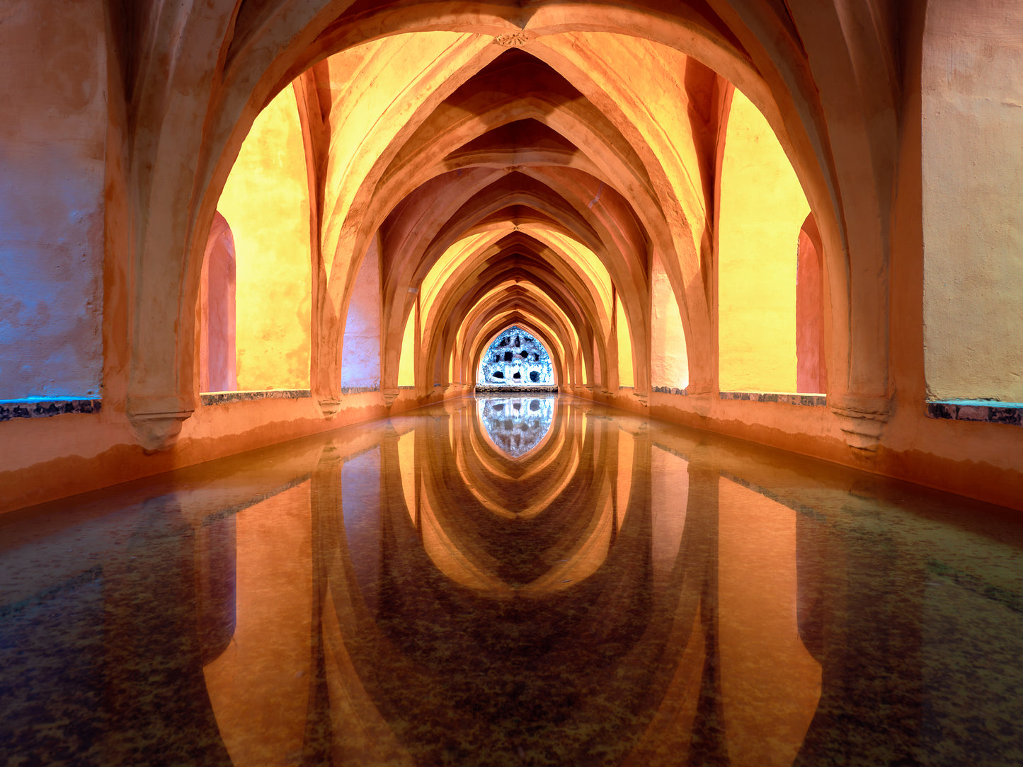 Reflections inside the Maria de Padilla Baths in Seville with arches mirrored in still water