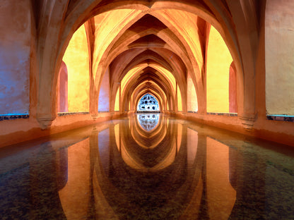 Reflections inside the Maria de Padilla Baths in Seville with arches mirrored in still water
