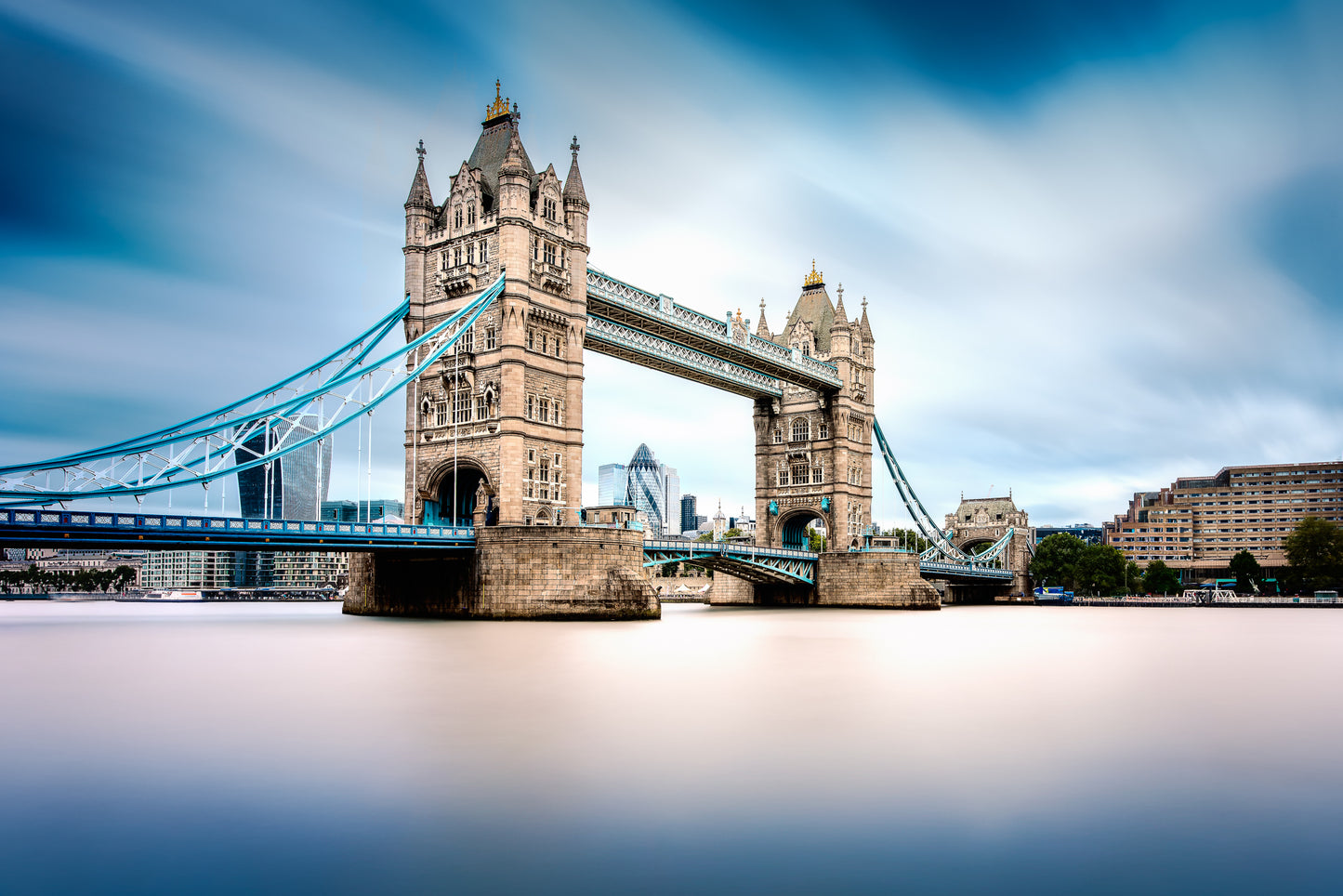 Long exposure photograph of Tower Bridge in London with smooth water and dramatic sky