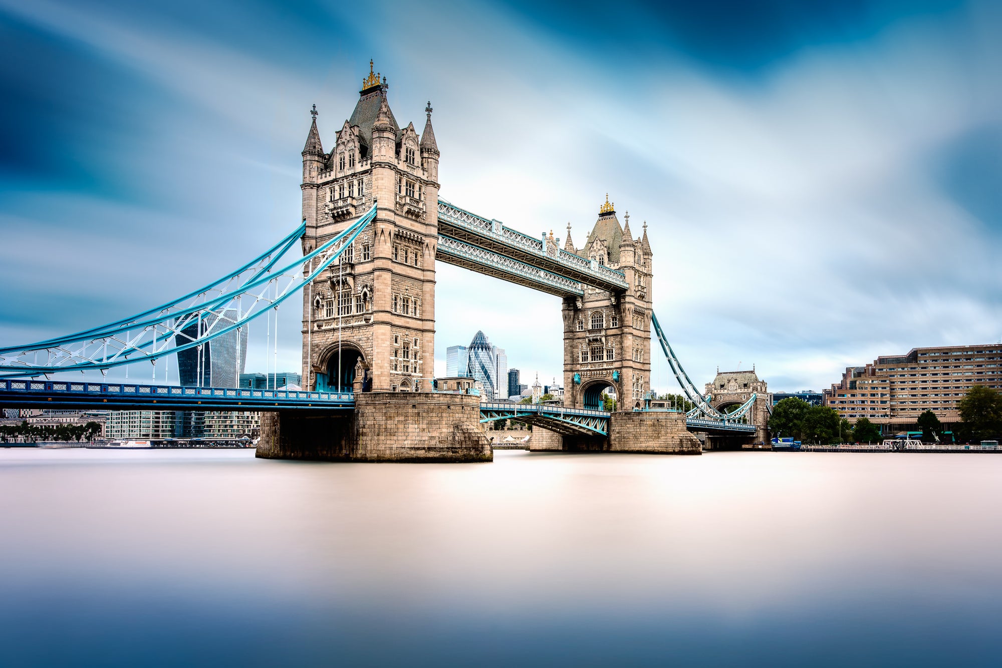 Long exposure photograph of Tower Bridge in London with smooth water and dramatic sky