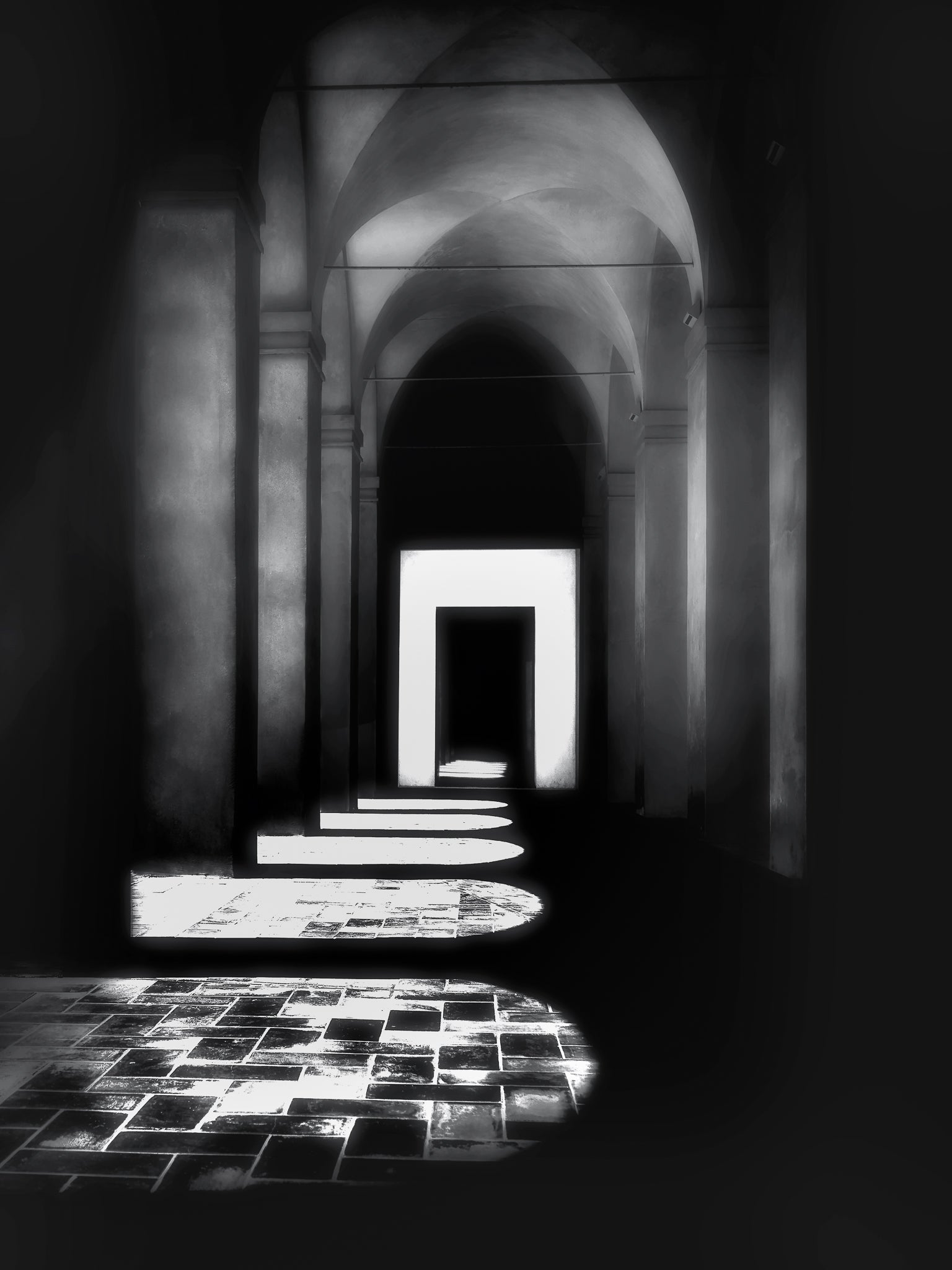 A fine art black and white photograph taken in the Real Alcázar of Seville, showing a sunlit colonnade with strong geometric shadows and historic stone arches.