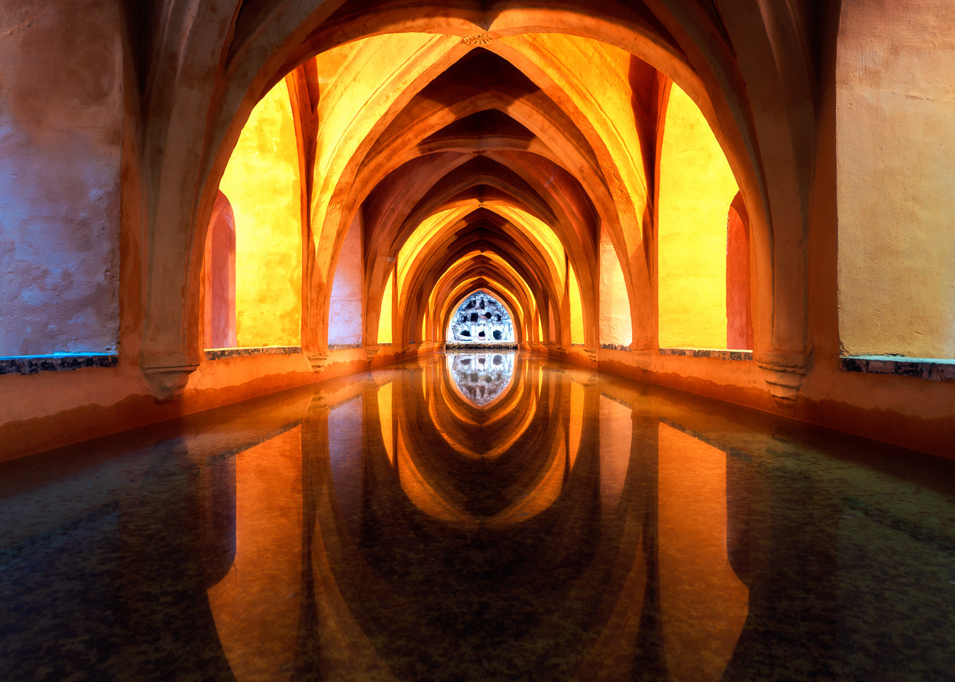 Golden Moorish-style arches reflected in still water, leading to a cool blue opening, fine art photograph by John Wright.