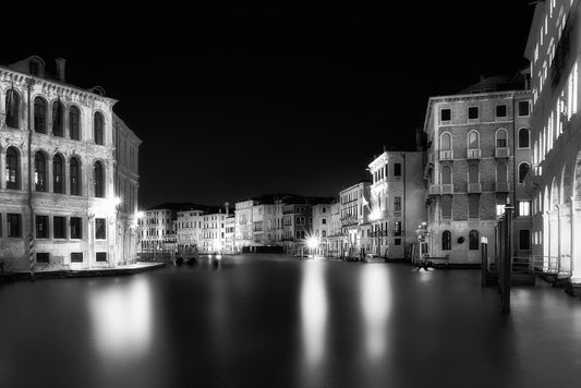 Black and white night photograph of Venice’s Grand Canal, with historic palaces and smooth water reflections captured in long exposure.