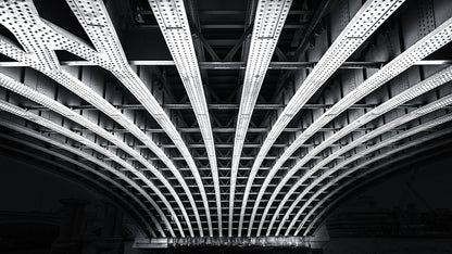 Black and white photograph of structural beams beneath a bridge in London showing symmetry and steel architecture
