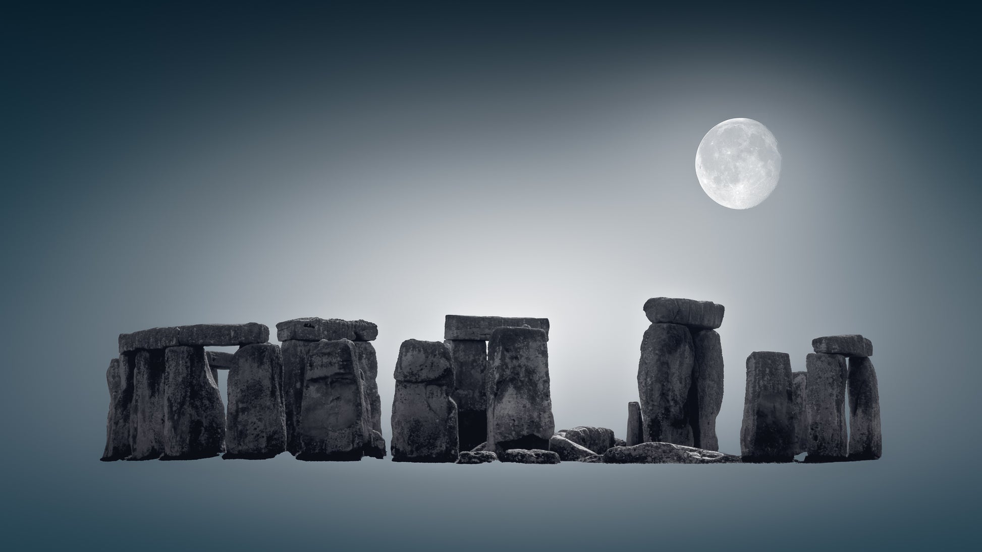 A fine art black and white photograph of Stonehenge in Wiltshire, England, with the full moon above the ancient stones at night.