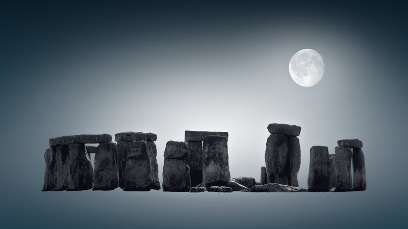 A fine art black and white photograph of Stonehenge in Wiltshire, England, with the full moon above the ancient stones at night.